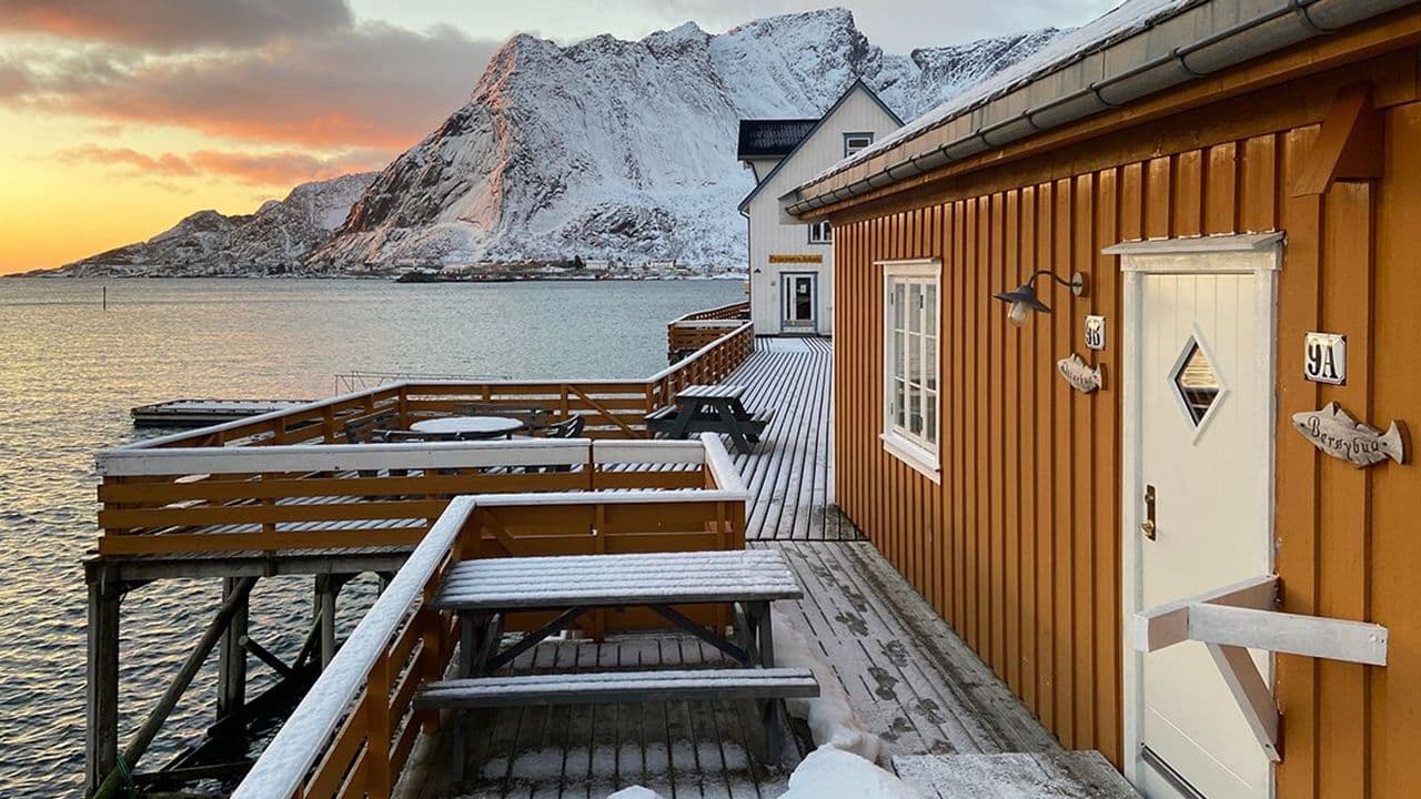 Nordnorsk rorbu som ligger værutsatt til helt ute ved vannet med hvit ytterdør.