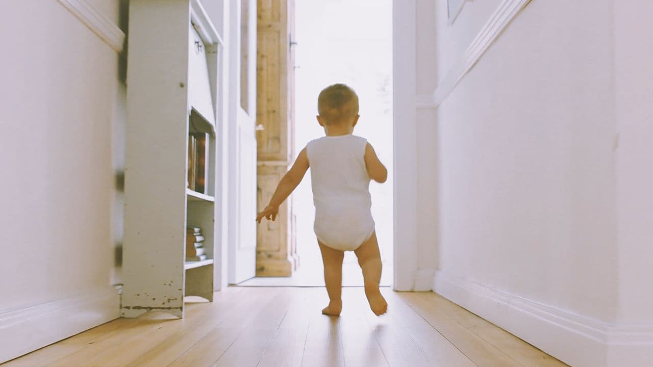 Baby som går på gulv med trinnlydplate under.