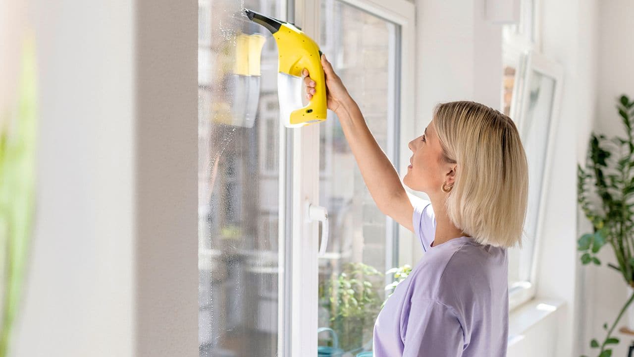 Kvinne som viser hvordan vaske vinduer med vindusvasker.