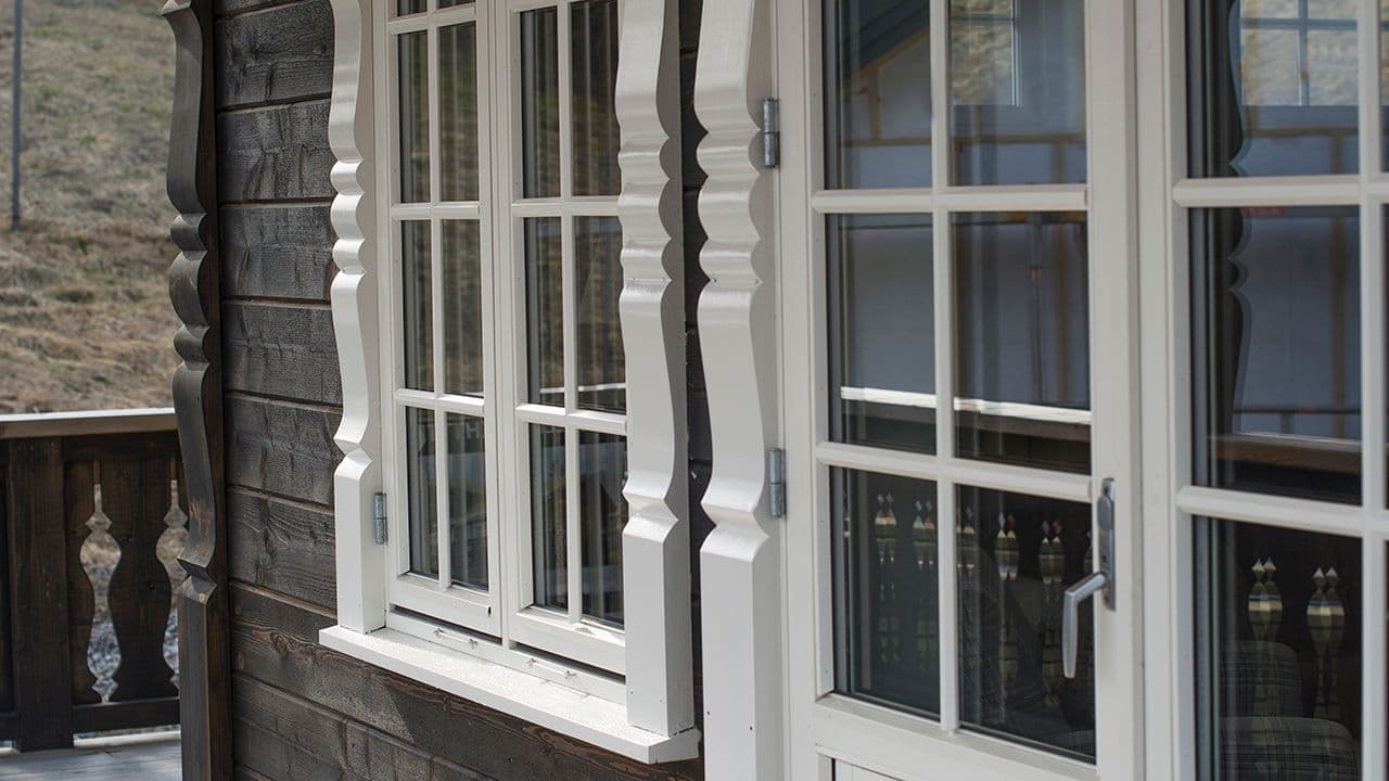 Hytte som har skiftet vinduer til nye vinduer med sprosser og utvendig karm med profil.