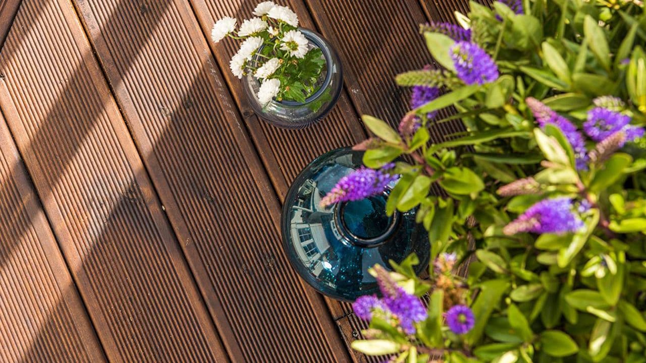 Nærbilde av brunoljet Duo terrassebord med sommerblomster på