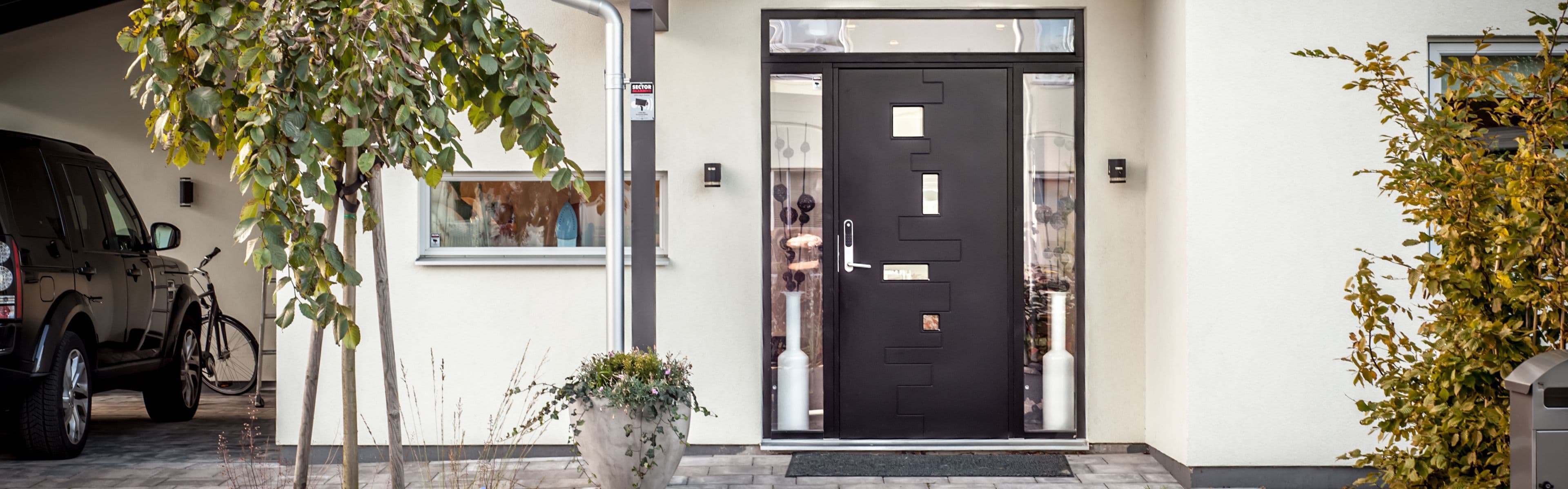 Hvitt murhus med sort ytterdør og sidefelt i glass for ytterdør inspirasjon.