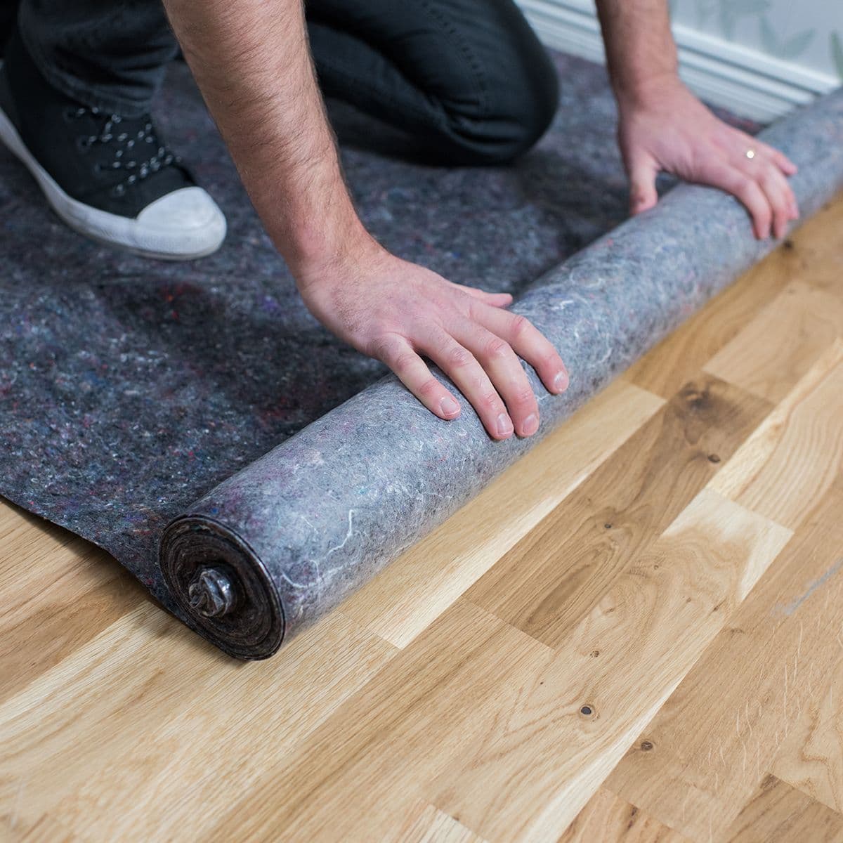 Mann som ruller ut dekkfilt på gulvet før maling.