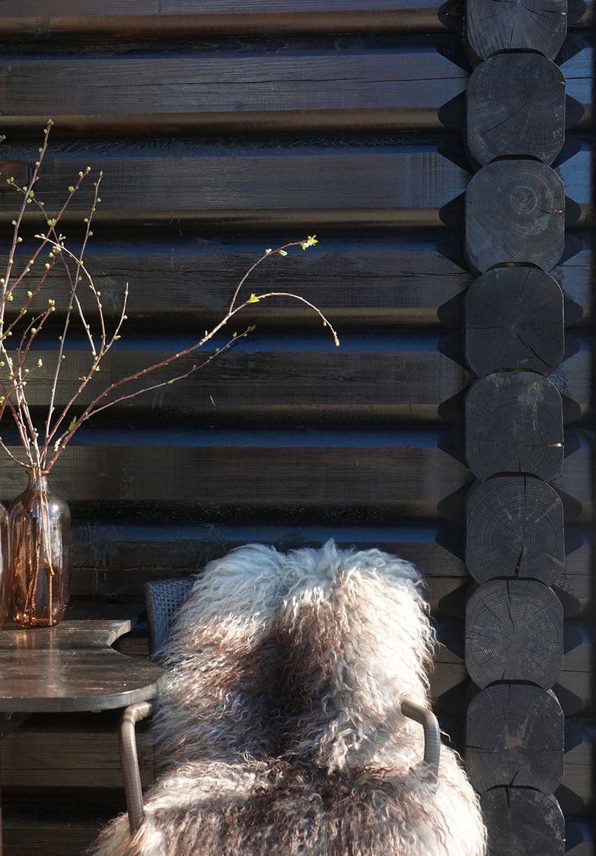 hagestol med saueskinn står inntil en brunbeiset hyttevegg