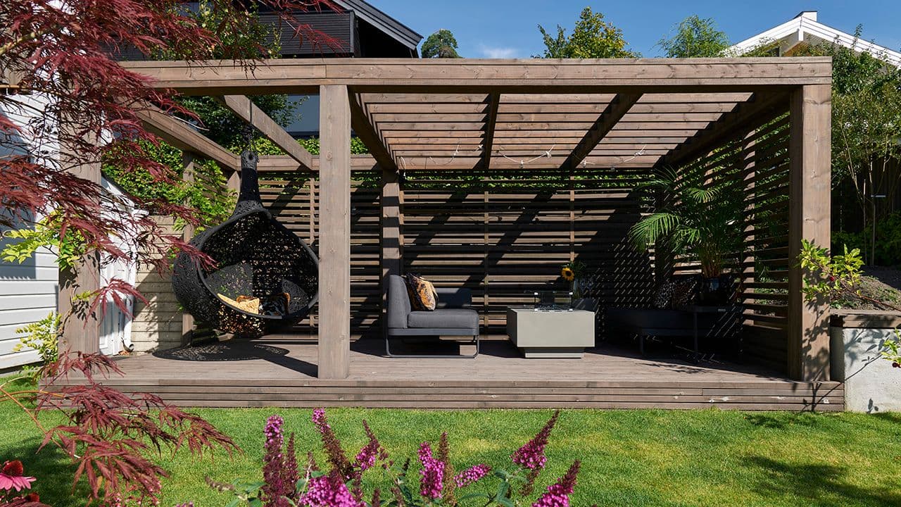 Platting med pergola og sittegruppe.