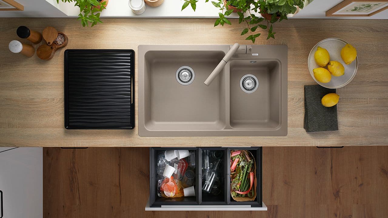 Beige blandebatteri og kjøkkenvask med smarte løsninger, og avfallssortering i hvitt kjøkken med benkeplate i heltre.