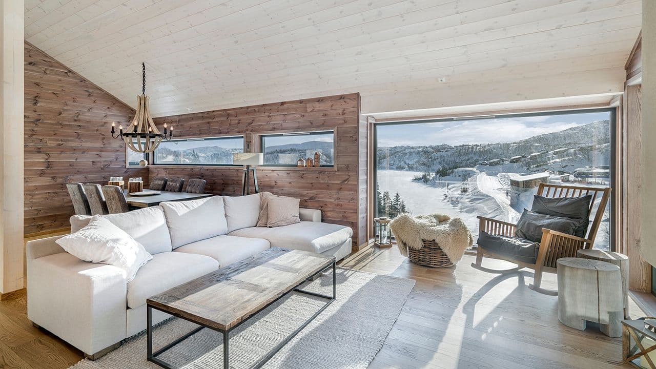 Fjellhytte med store nye vinduer i stue med hvit sofa.