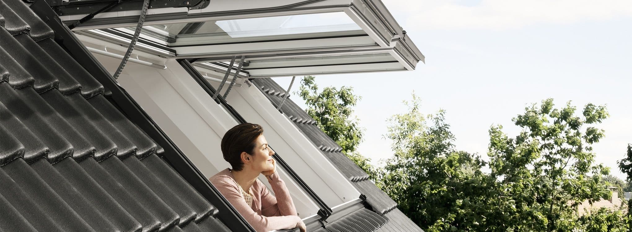 Dame kikker ut av et åpent takvindu.