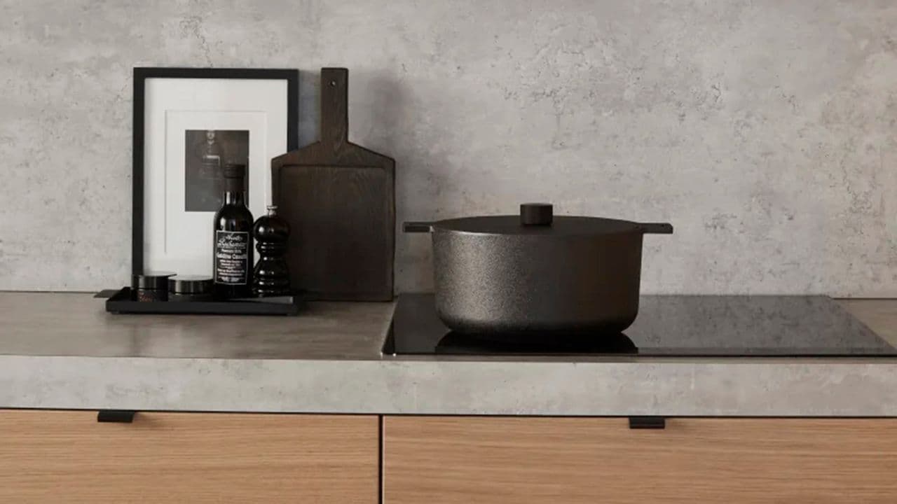 Grå laminat benkeplate og koketopp med kjele på i kjøkken med fronter i eik.