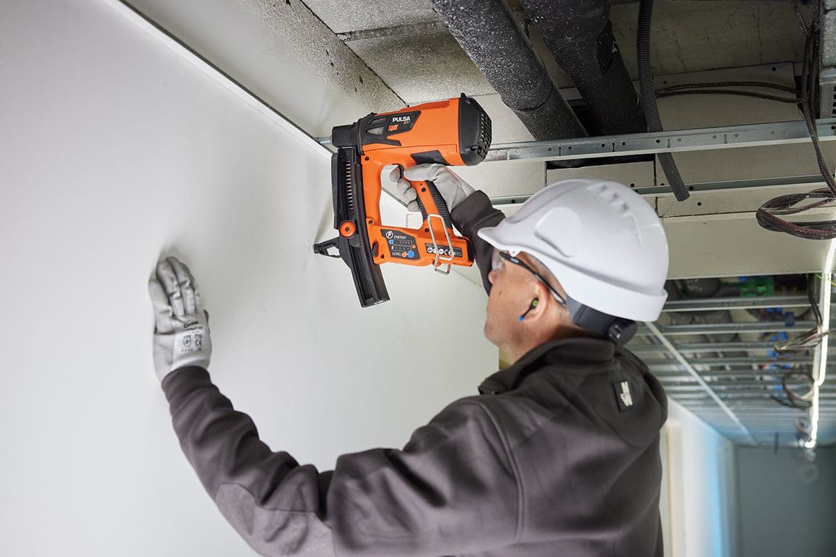 håndverker fester i betong med boltepistolen Pulsa P27