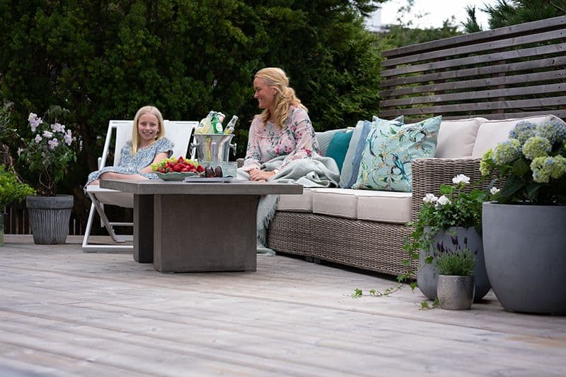 En jente og en dame som sitter på terrassen og smiler.