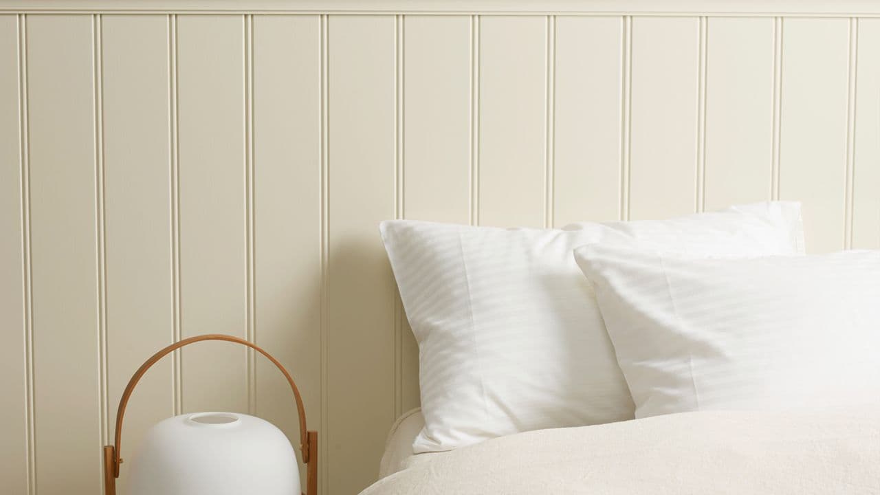 Soverom med hvitt sengetøy og JOTUN LADY 1931 Kokos på veggene.