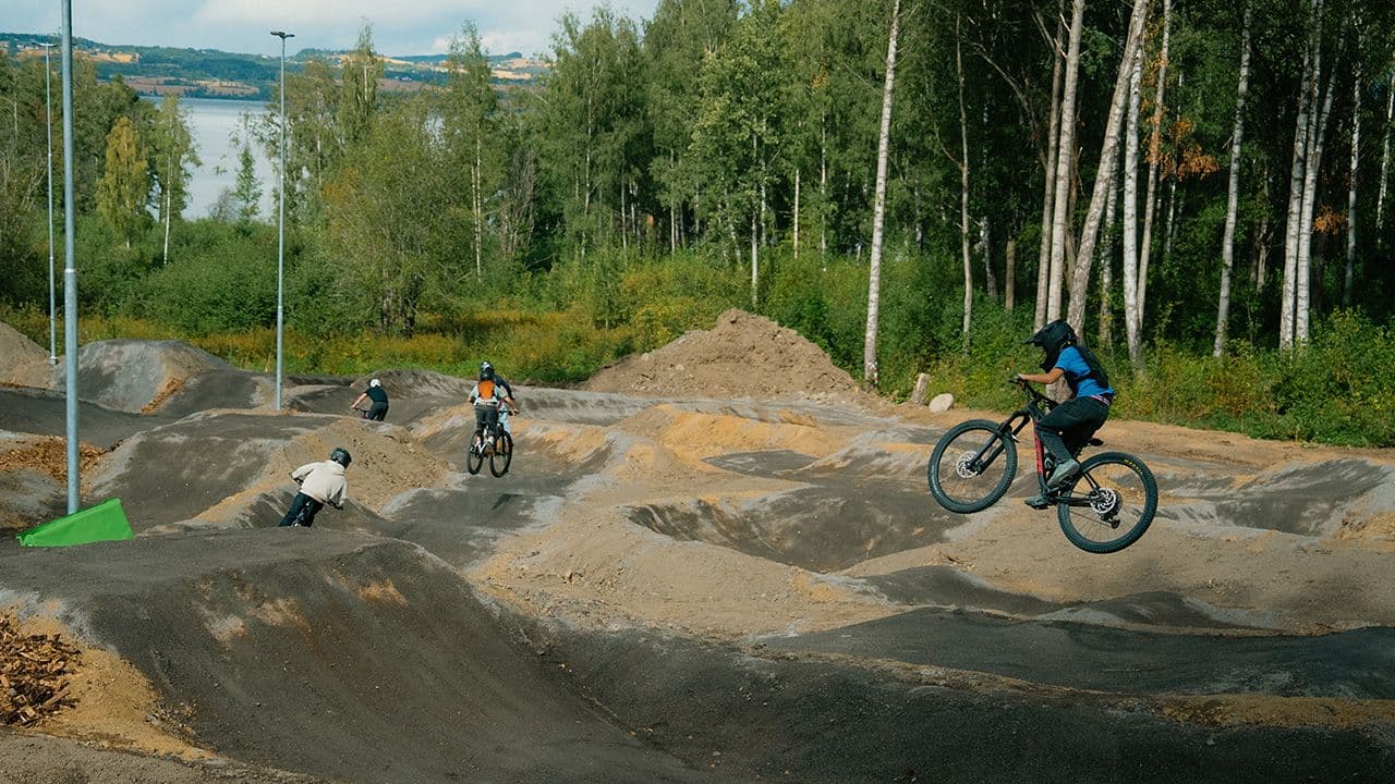 Ungdommer som hopper og sykler på hinder i en sykkelpark.