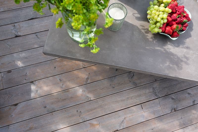 Terrassebord med et spisebord med frukt og planter.