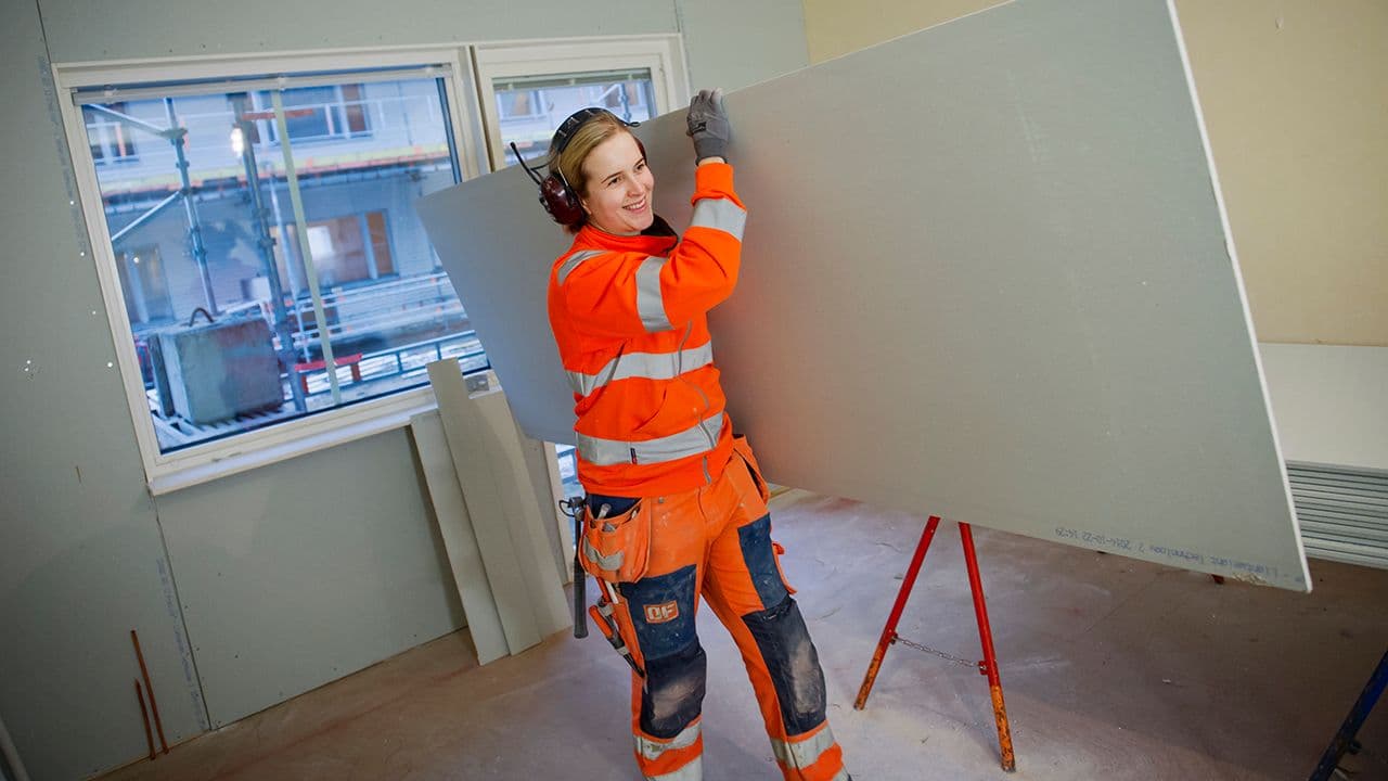 Kvinne bærer gipsplater fra Gyproc i en leilighet