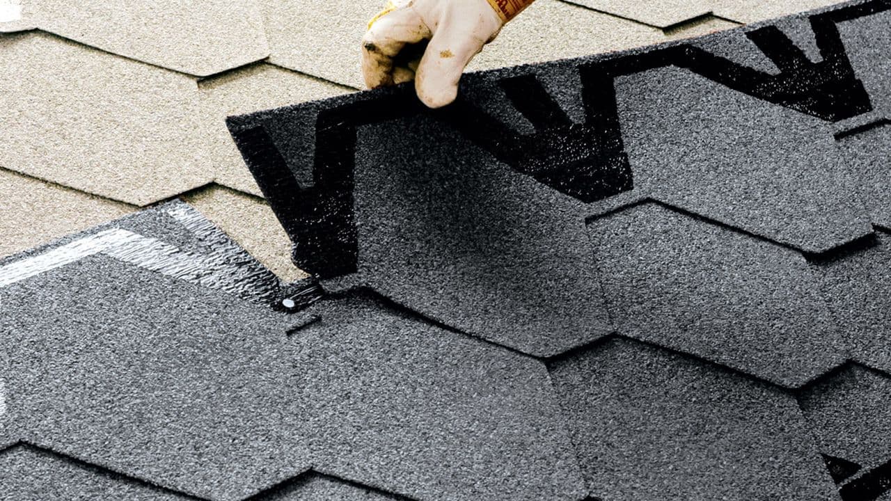 Nærbilde av legge nytt tak på gammelt tak med takshingel.