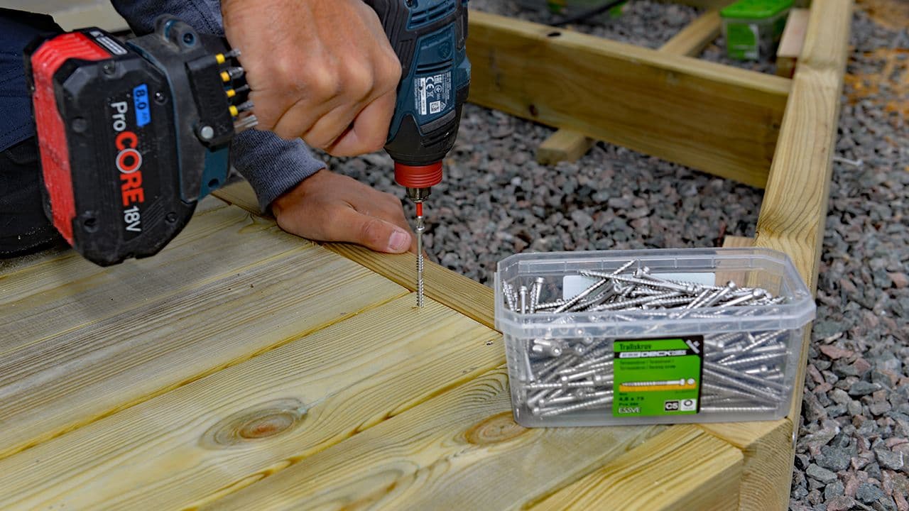 Håndtverker som skrur inn ESSDECK Max terrasseskrue med drill.