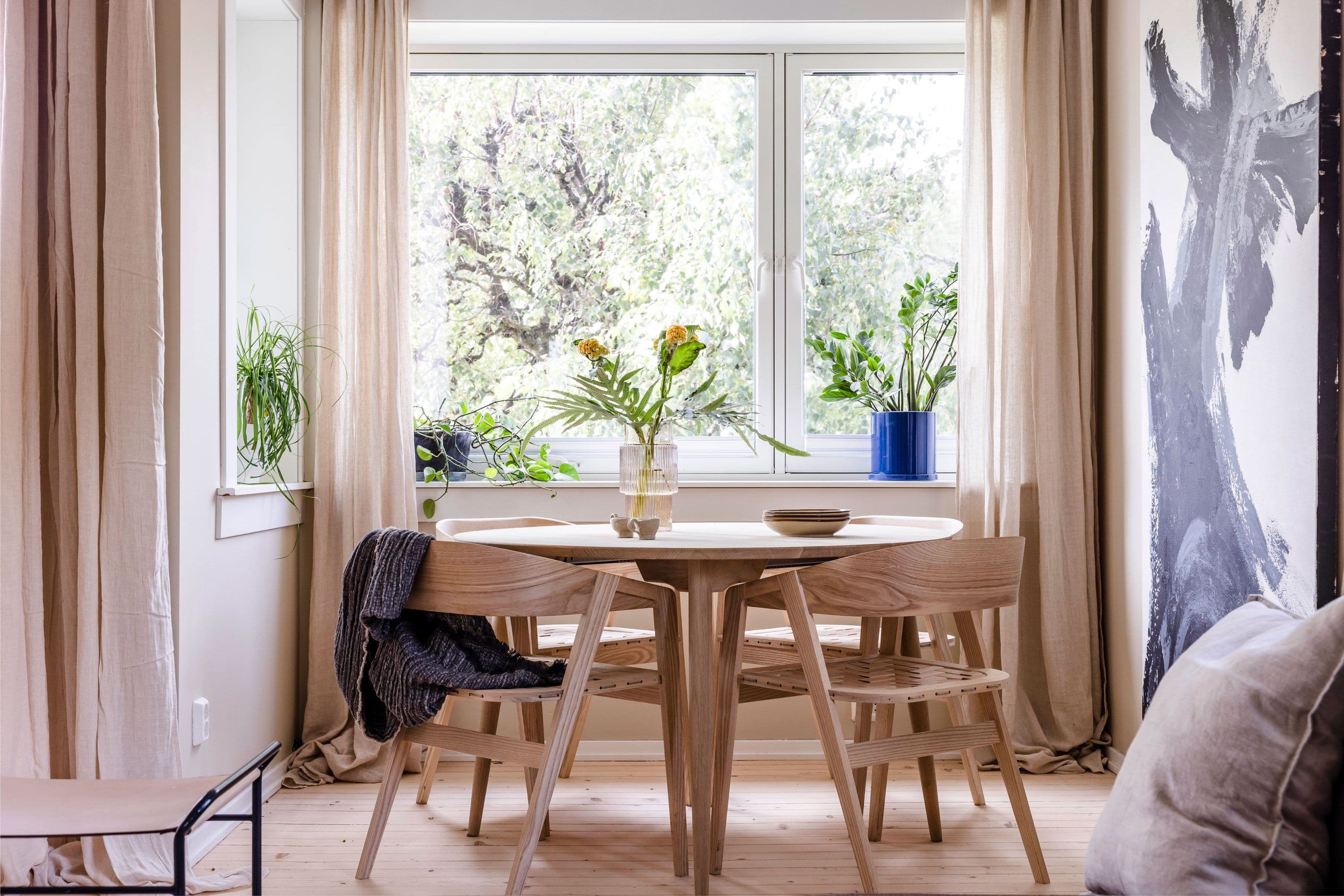 Spisestue med rundt bord og stort vindu.