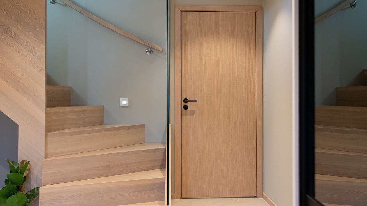 Lys innerdør i eik med sort dørhåndtak og dørvrider.