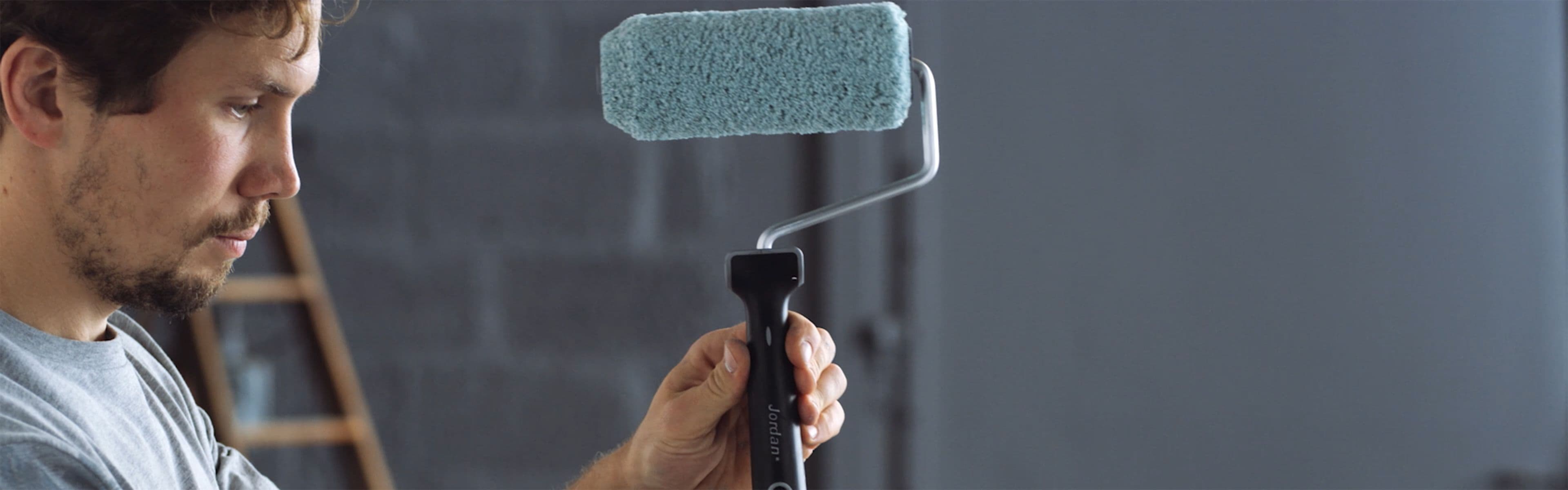 Mann som holder malingsrulle på skaft