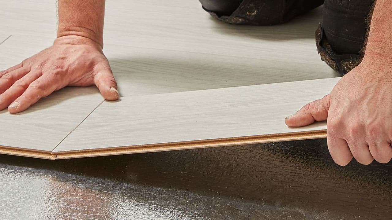 Nærbilde av hender til en person som legger gulv.